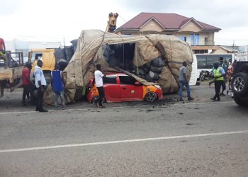 Driver and passenger escape unhurt as charcoal truck falls on taxi at Achimota