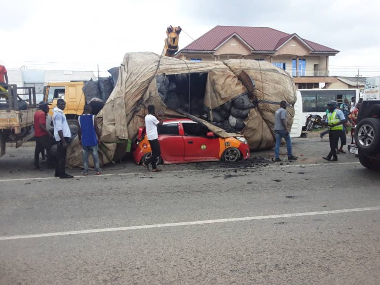 Driver and passenger escape unhurt as charcoal truck falls on taxi at Achimota